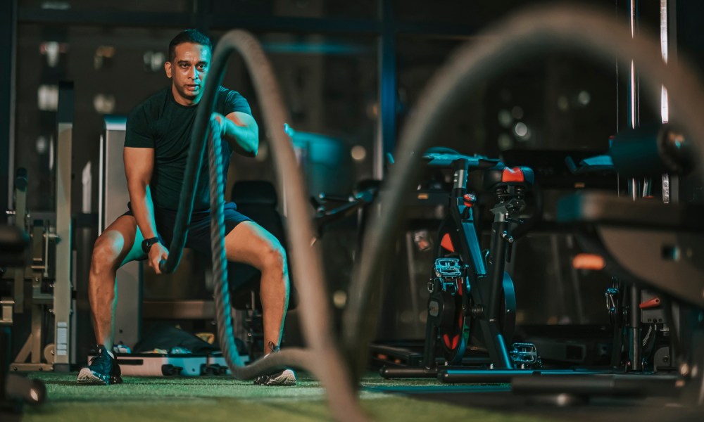 A man using battle ropes in a gym