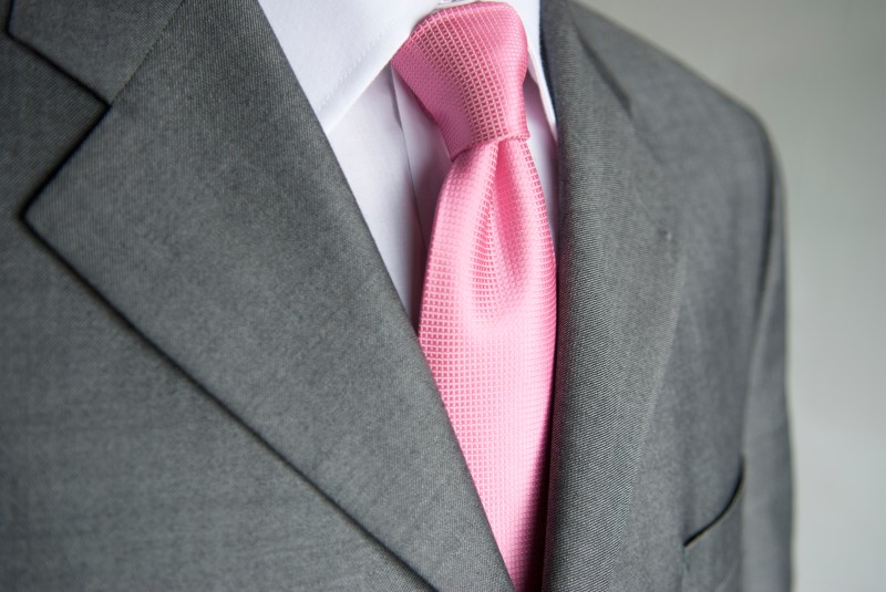 Close-up bright pink necktie makes a colorful contrast to a neutral gray suit on businessman